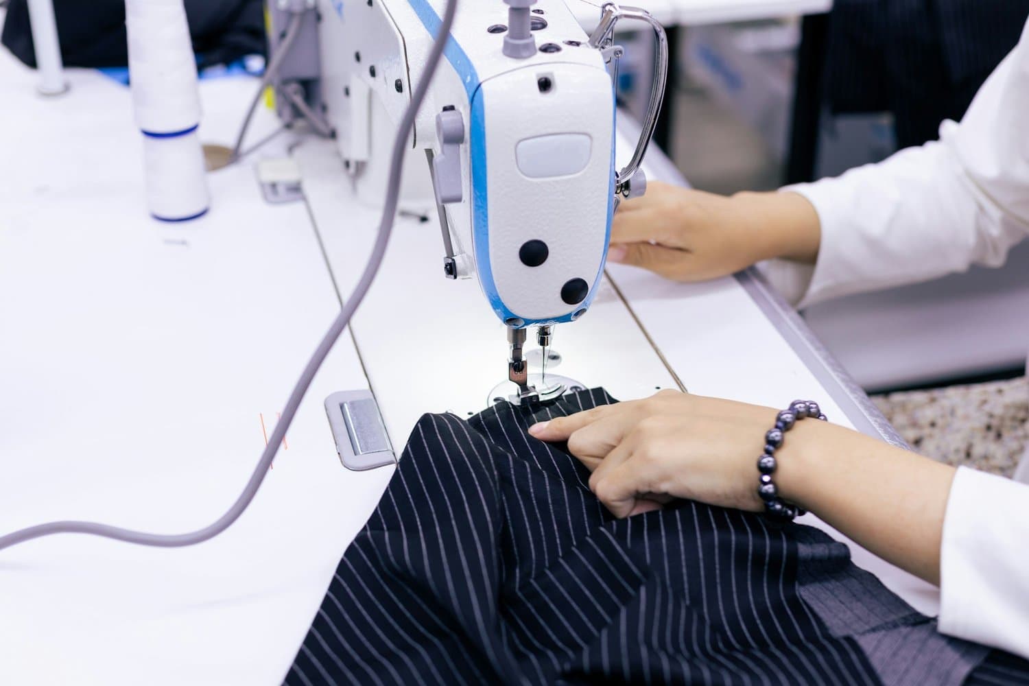 Tailor sewing a pinstriped suit in a workshop, highlighting local expert clothing services in Tampa such as alterations, dry cleaning, and laundry