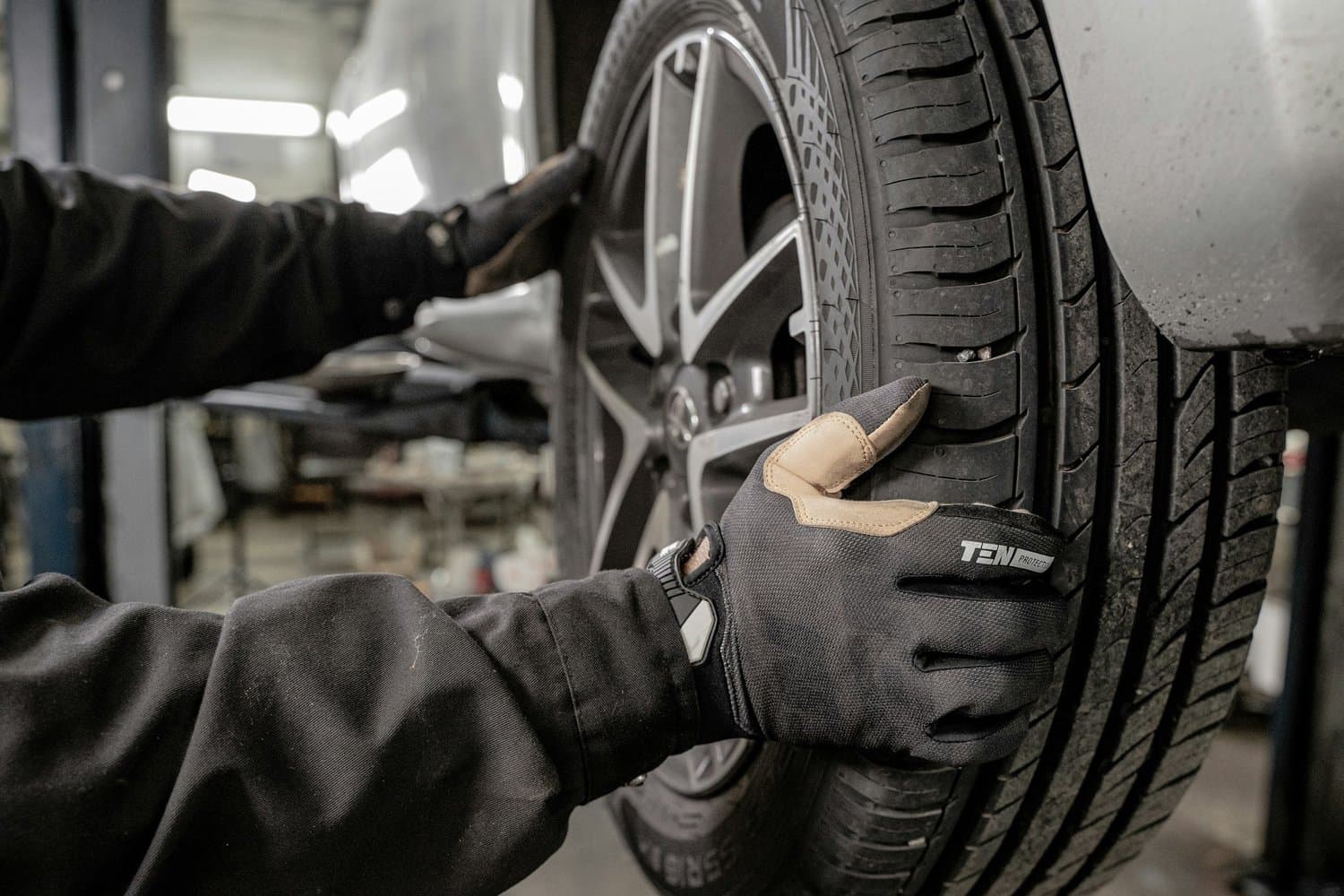 Mechanic replacing a car tire at a local auto repair shop, showcasing professional automobile services in Tampa including brakes, tire replacement, and bodywork