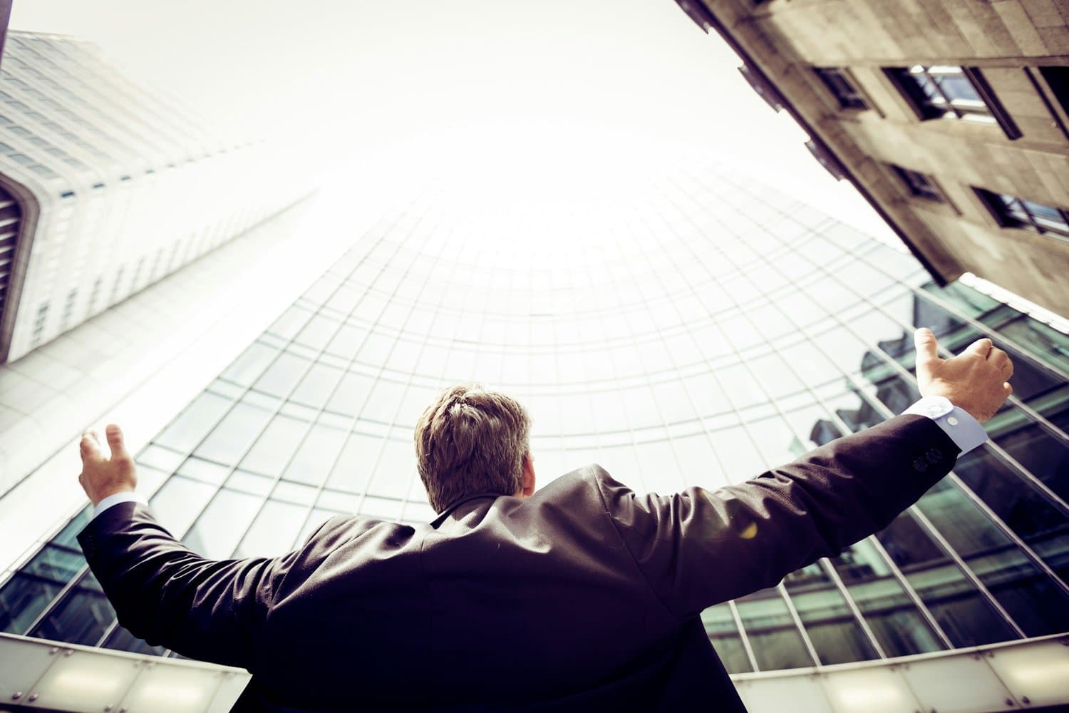 Man with arms raised looking at skyscrapers, representing local personal development services in Tampa including coaching, tutoring, fitness, nutrition coaching, skill development, time management, and therapy
