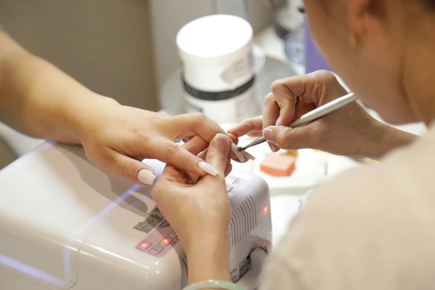 Nail technician providing a manicure to a client in a salon, representing local personal care services in Tampa including skincare, spa treatments, massage therapy, hair salon and braiding, lash and brow services, and nail care